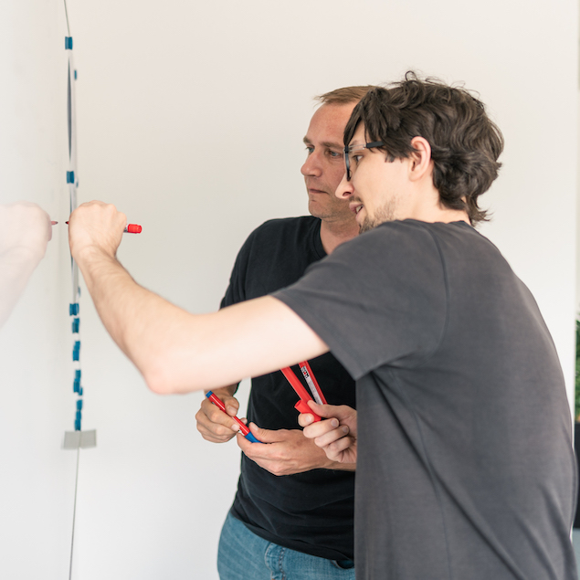 Zwei Lorent IT Mitarbeiter mit Stiften stehen vor Whiteboard