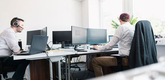 Lorent IT Mitarbeiter an zwei Schreibtischen vor Monitoren