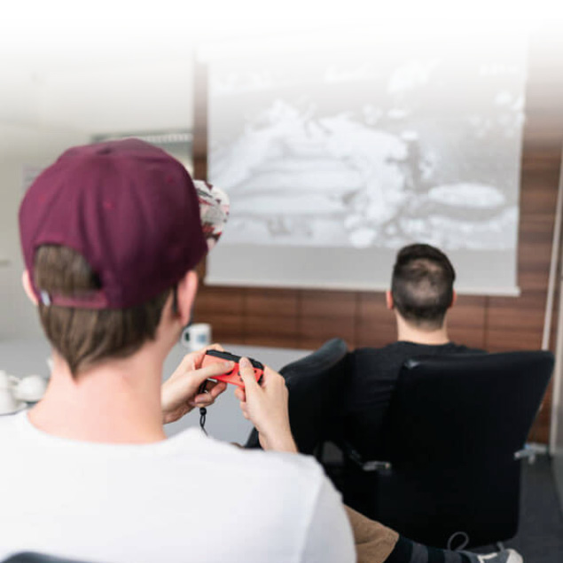 lorent-it-mitarbeiter-gaming Lorent IT Mitarbeiter sitzen vor Leinwand und spielen Computerspiele